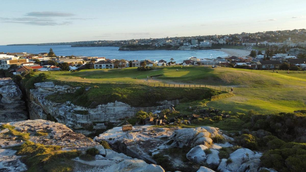 Aerial view of Bondi Golf & Diggers Club's clifftop course above Bondi Beach, with the ocean, cliffs and Sydney coastline beyond.