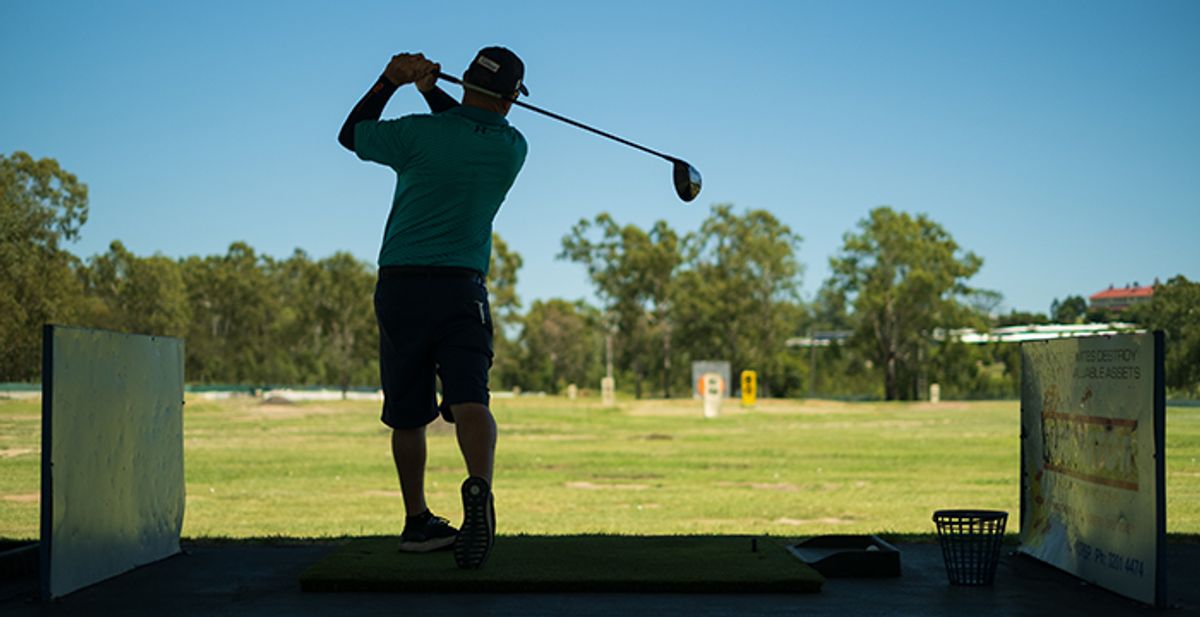 A golfer teeing off from a driving range bay at Ipswich Golf Driving Range & Putt Putt