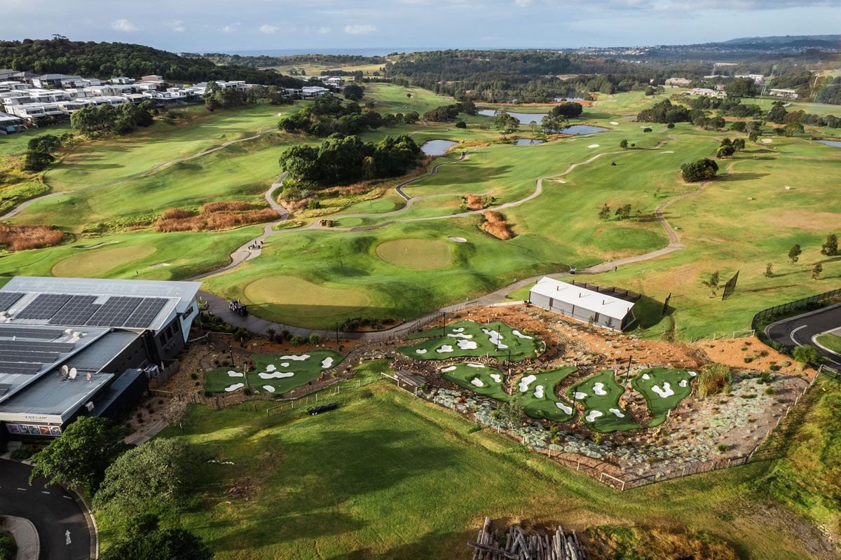 Aerial view of The Links Shell Cove golf course, showing fairways, ponds, the clubhouse, and putting greens with the ocean in the distance.
