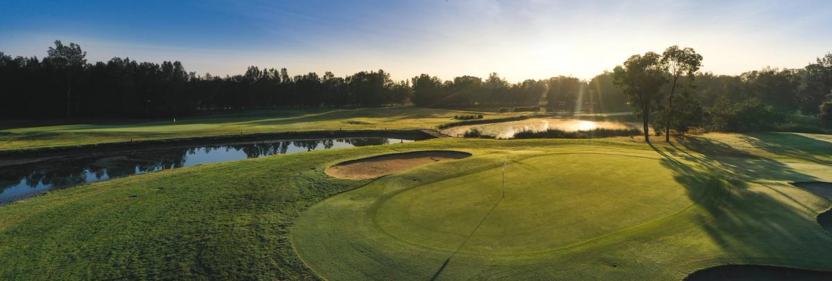 Sunrise over a green and pond at Penrith Golf Club