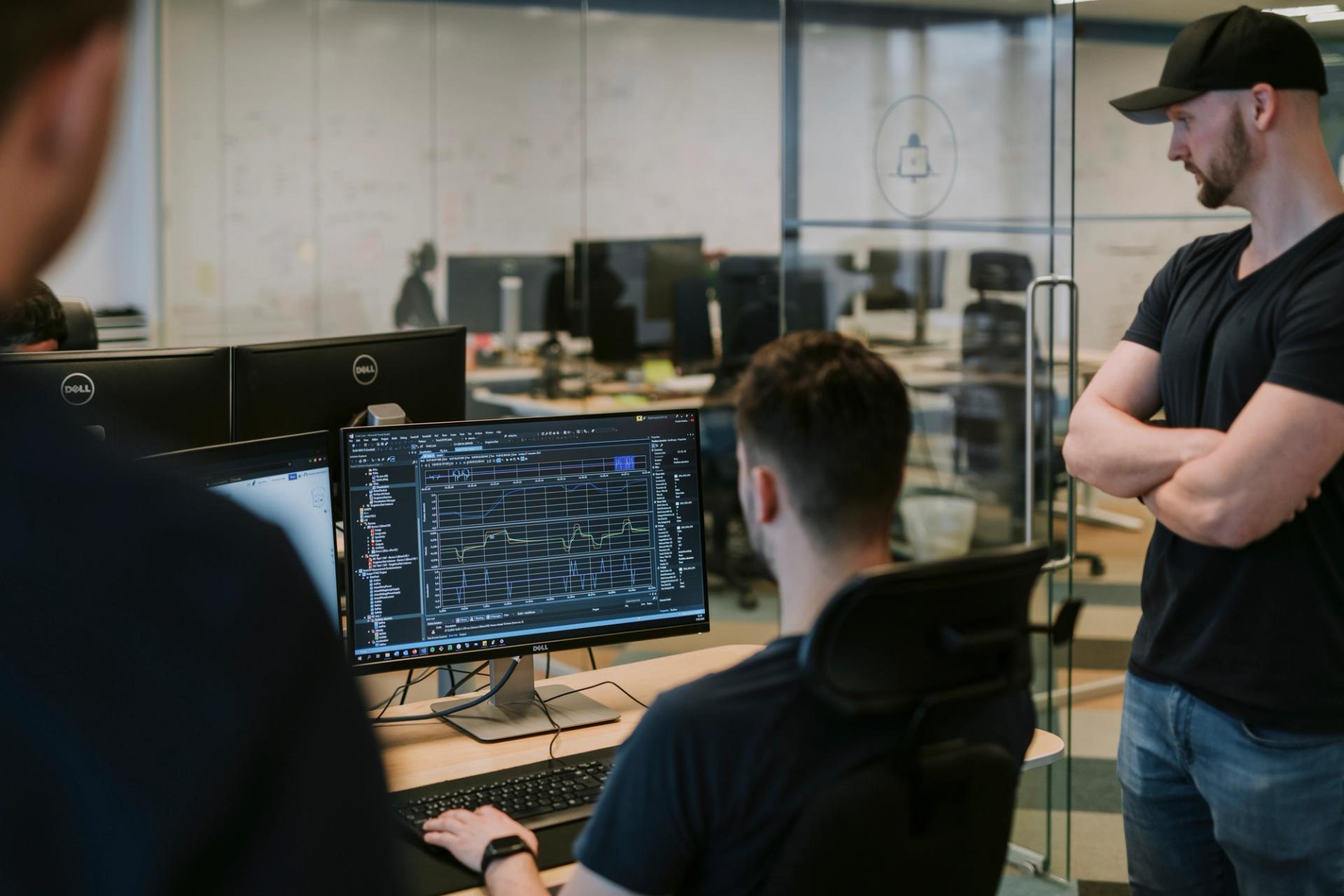 Three men looking at a graph on a computer