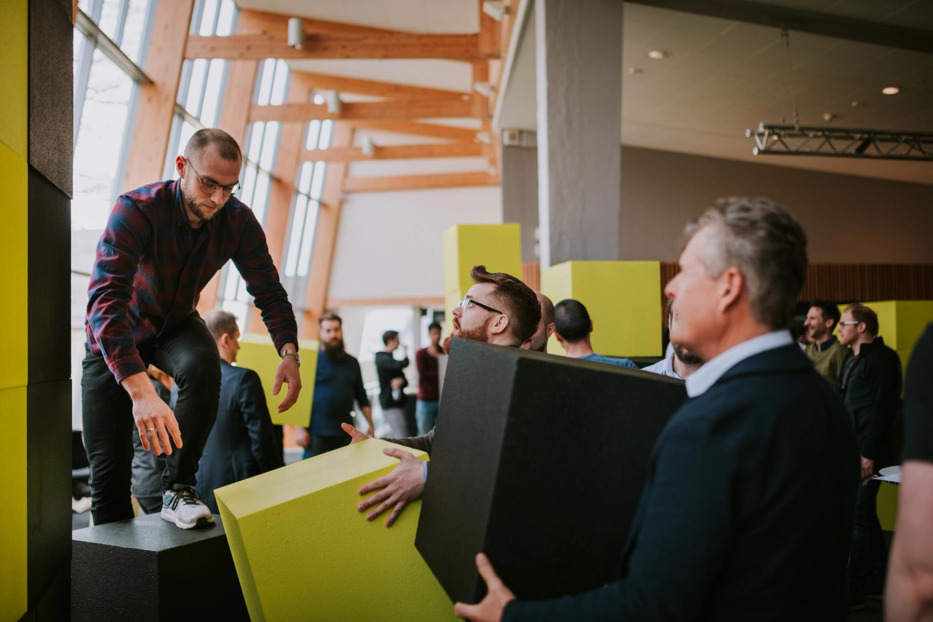 Three Solwr employees building a tower with foam cubes during a company workshop event.