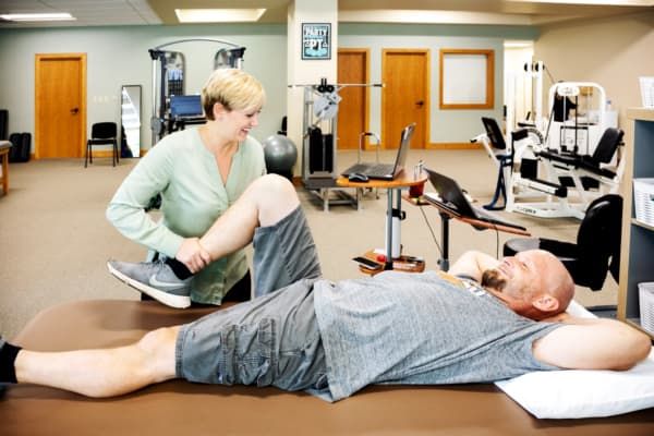 Female physical therapist working on man's leg