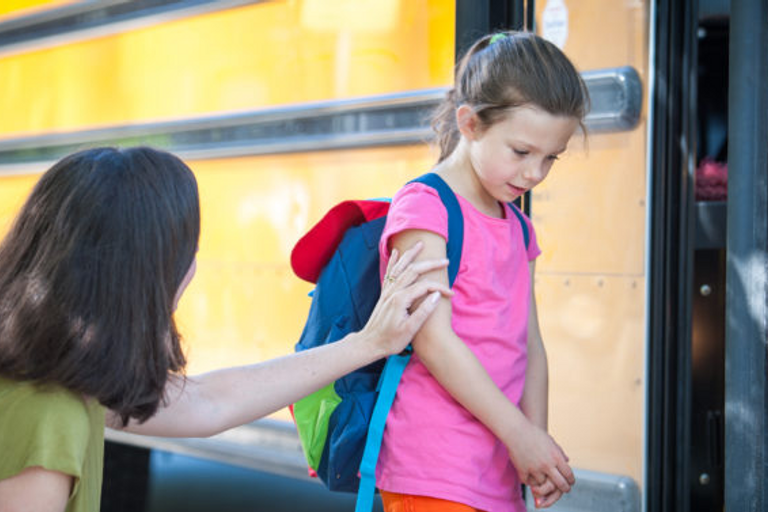 Mother putting her daughter on the school bus