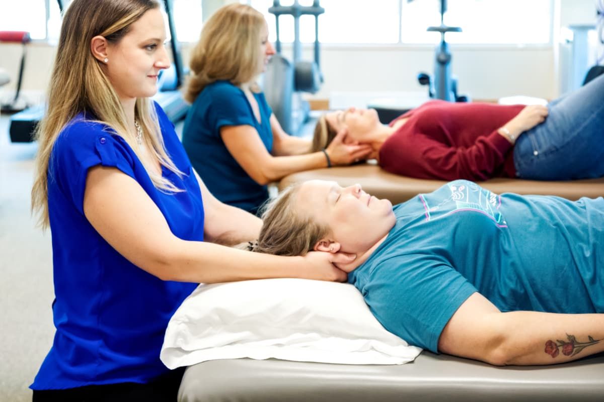 Female physical therapist with her hands under a patient's neck
