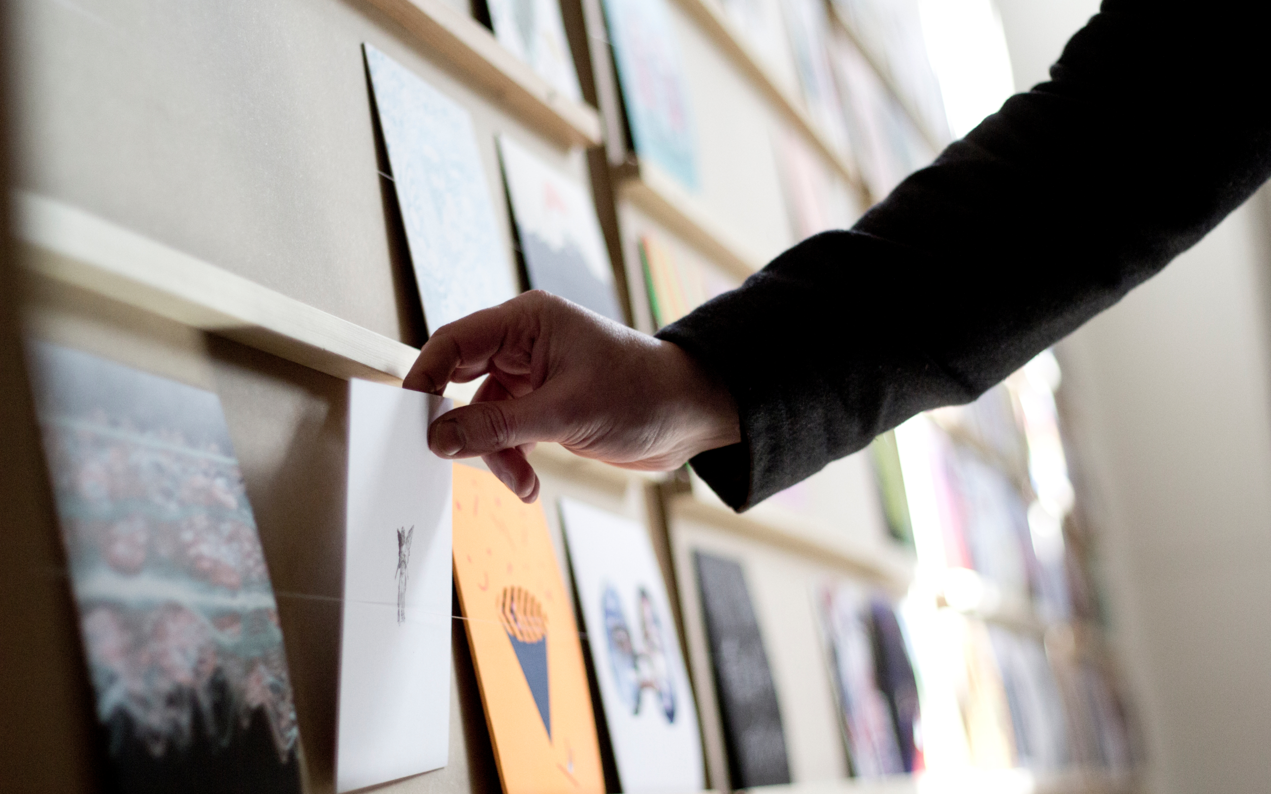 Wall of different record sleeves, with a hand picking one up