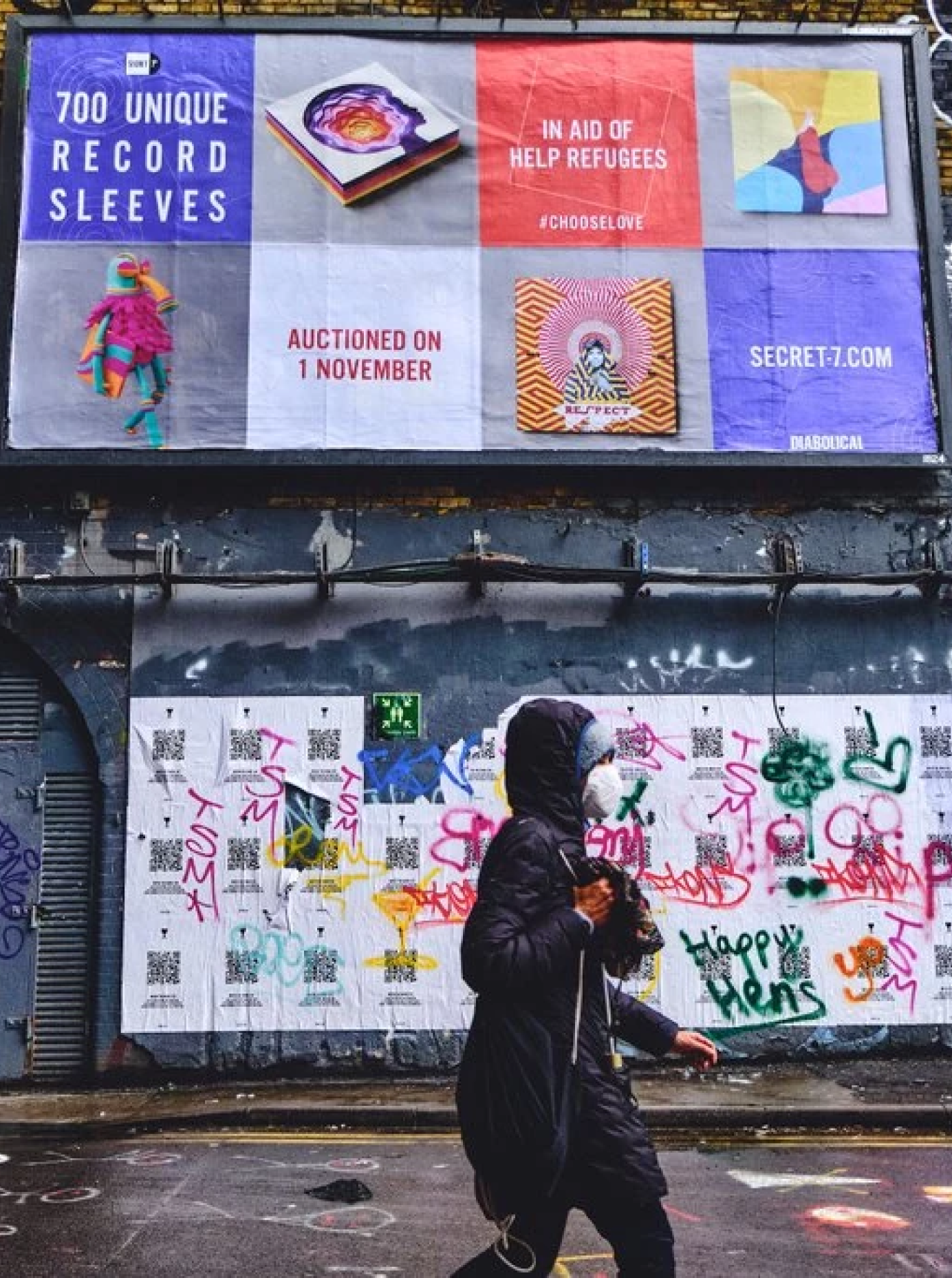 person walking past secret 7 posters in London