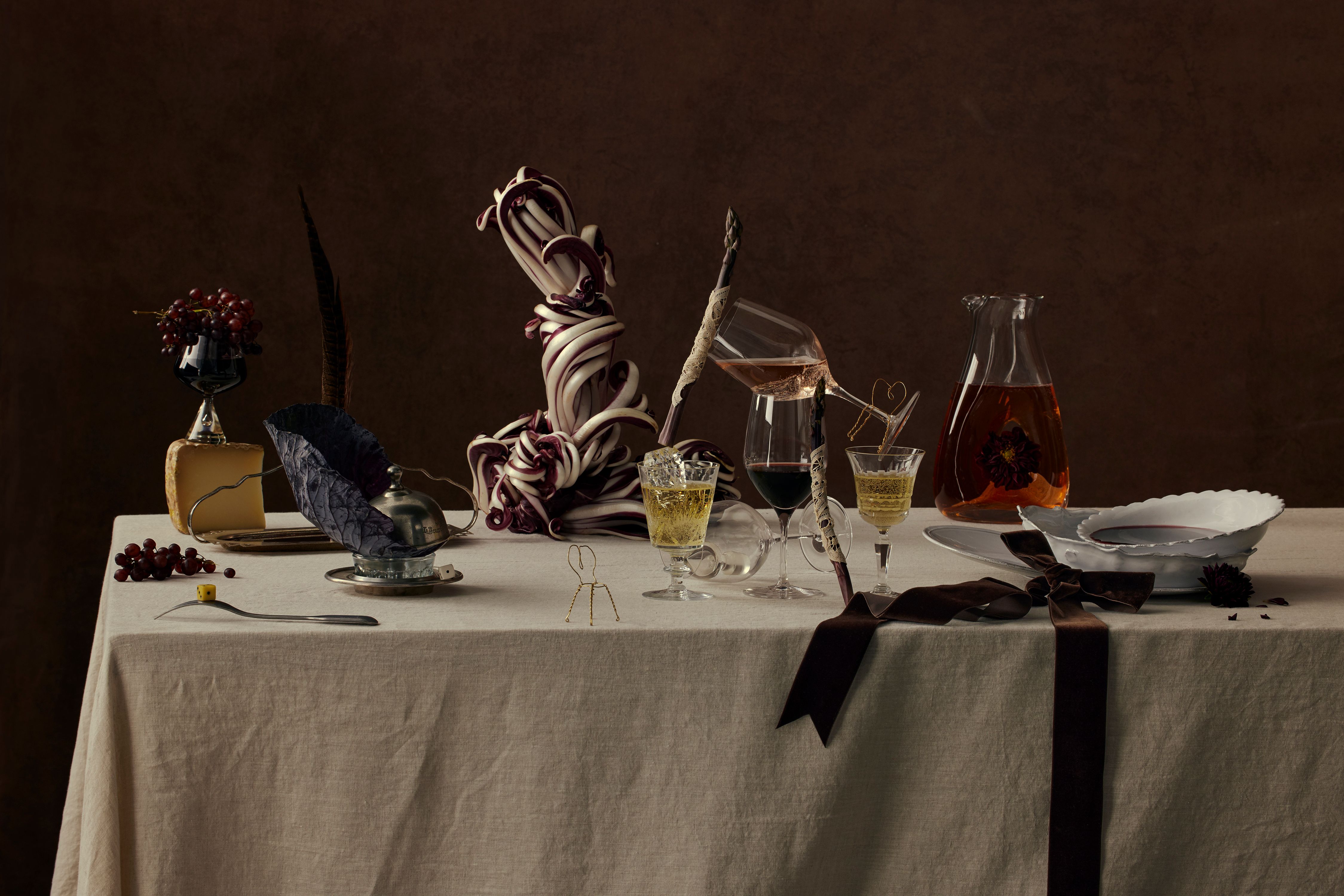 A fine dining table full of various wine related items, such as grapes, wine glasses and decanters