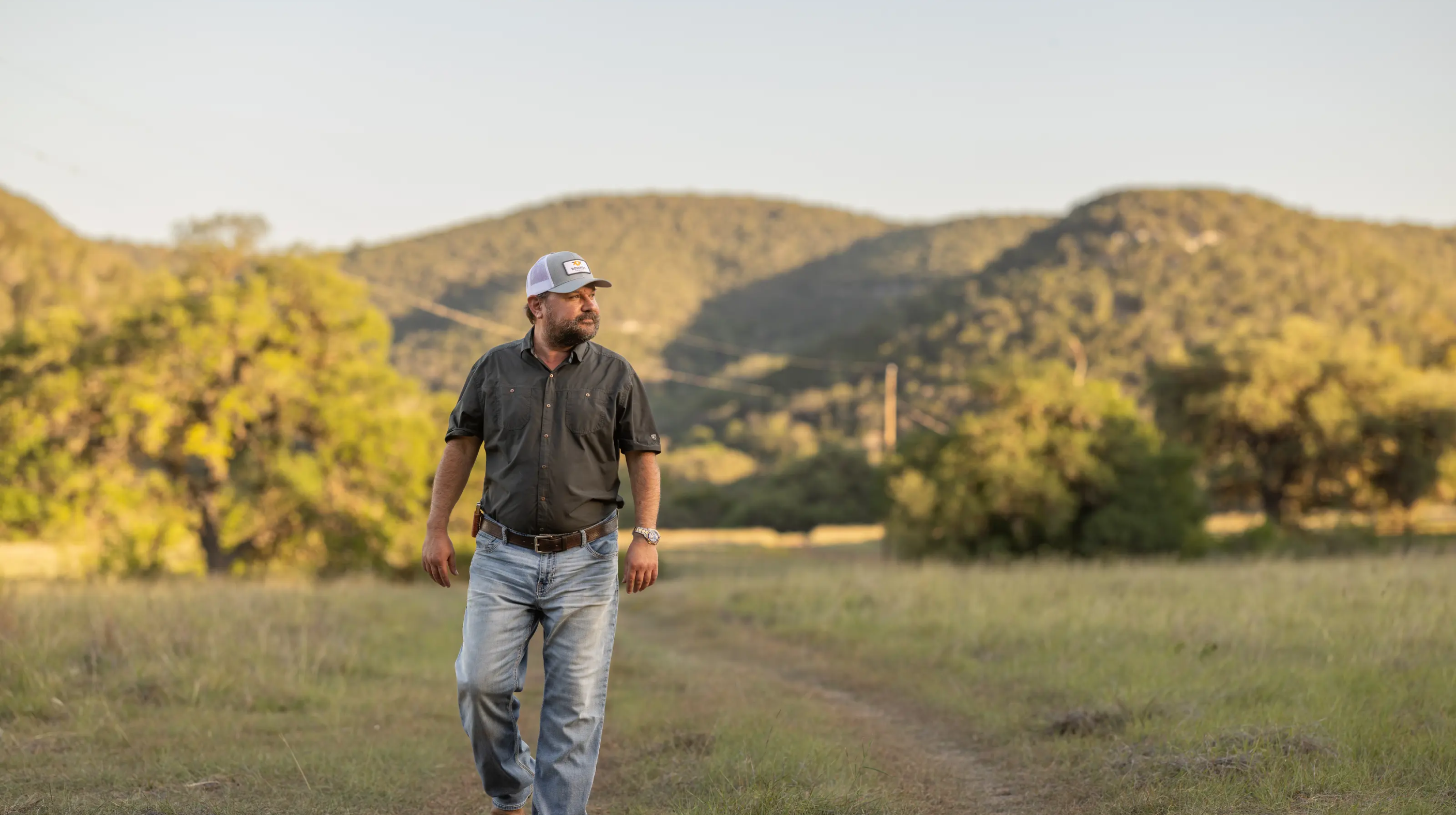 A man, Brandon Bownds, walking in the outdoors on a ranch