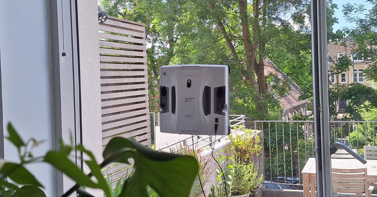 Robot perač prozora pričvršćen na staklenu površinu terase tokom automatskog čišćenja.