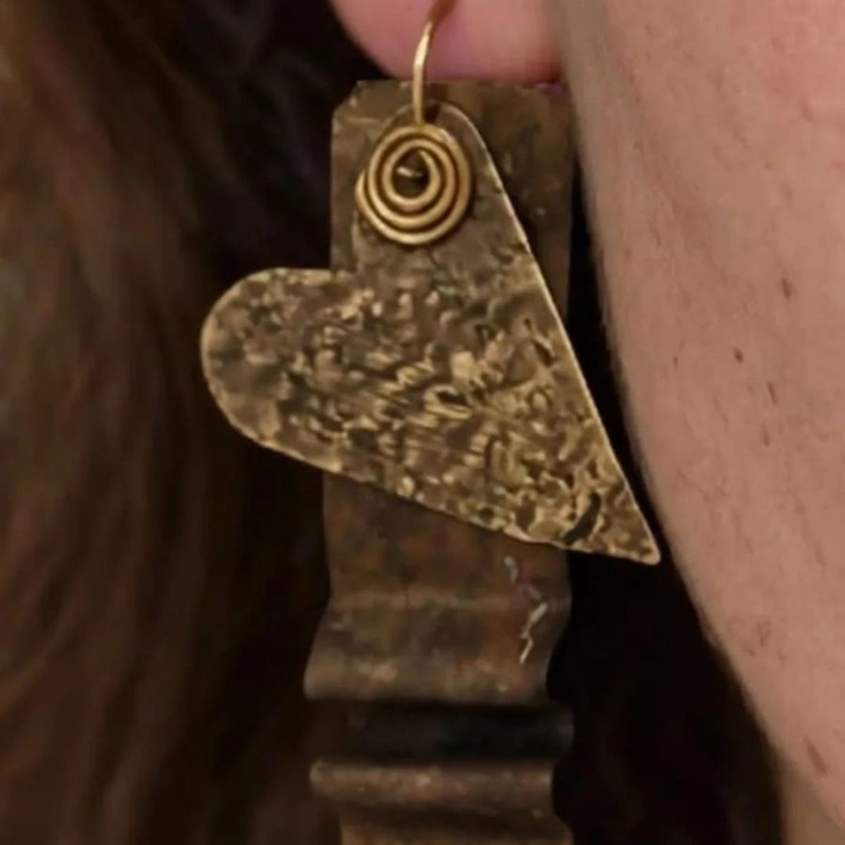 Orecchino in ottone a forma di cuore con una spirale di filo, indossato