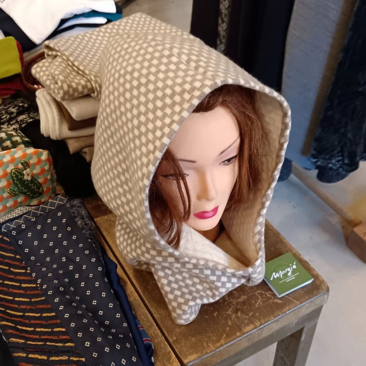 Balaclava in tessuto beige e bianco a piccolo motivo geometrico, su un manichino