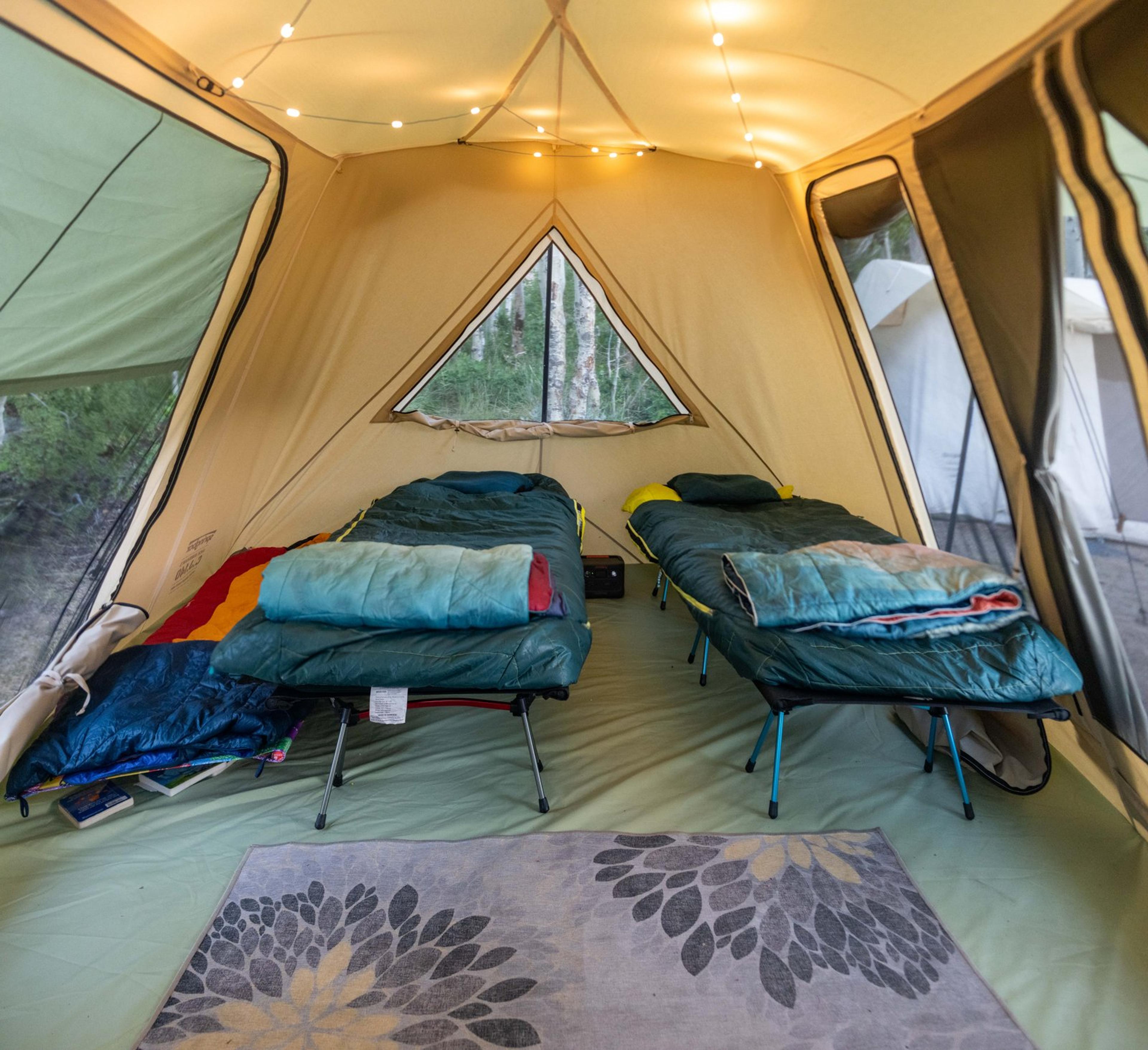 Interior of Springbar tent with cots, rug, and string lights creating a cozy glamping atmosphere Interior of Springbar tent with cots, rug, and string lights creating a cozy glamping atmosphere