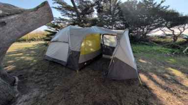 A fully assembled North Face Wawona 6 tent with the rainfly on and vestibule extended at a campsite