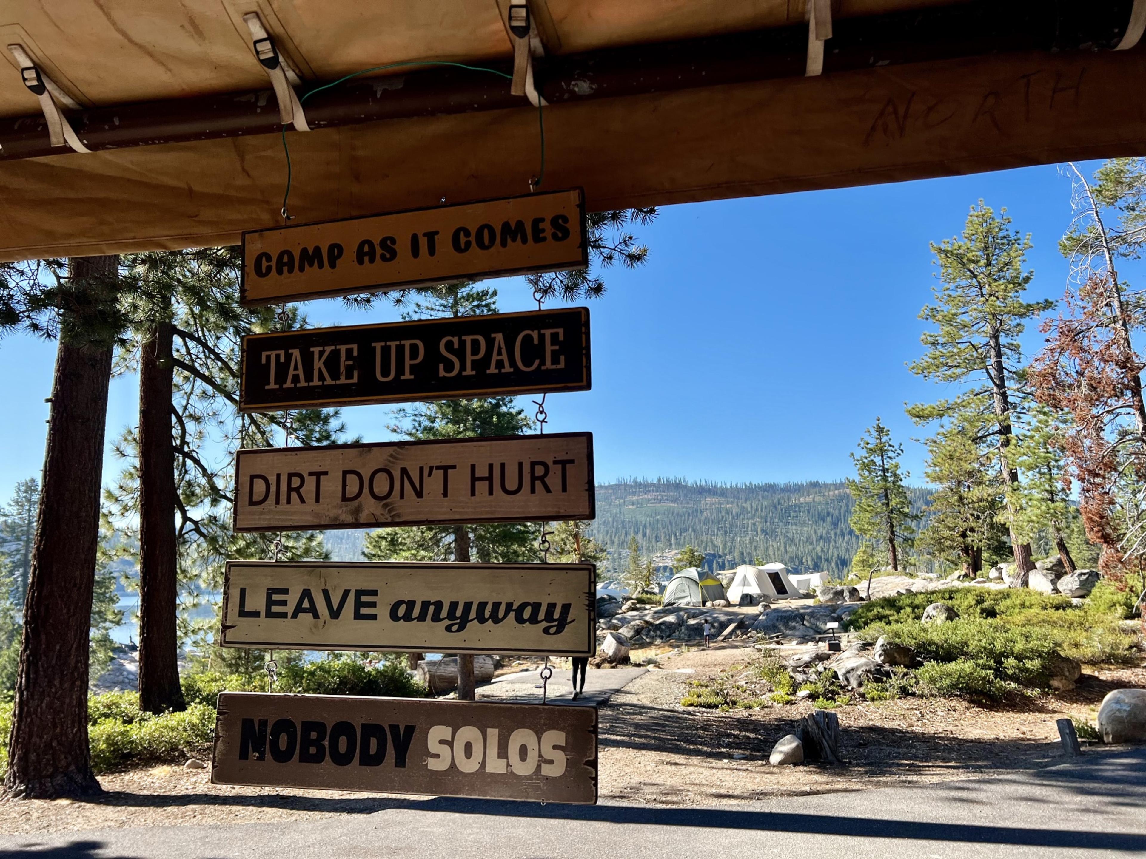 Wooden camp signs reading Camp As It Comes, Take Up Space, Dirt Don't Hurt, Leave Anyway, and Nobody Solos, hanging at camp above New Spicer Meadow Reservoir Wooden camp signs reading Camp As It Comes, Take Up Space, Dirt Don't Hurt, Leave Anyway, and Nobody Solos, hanging at camp above New Spicer Meadow Reservoir
