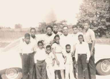 Historic family photo of a Black American family on a Memphis farm in the mid-20th century, showing Sally Steele's father as a young child seated in the front row with his parents and nine siblings