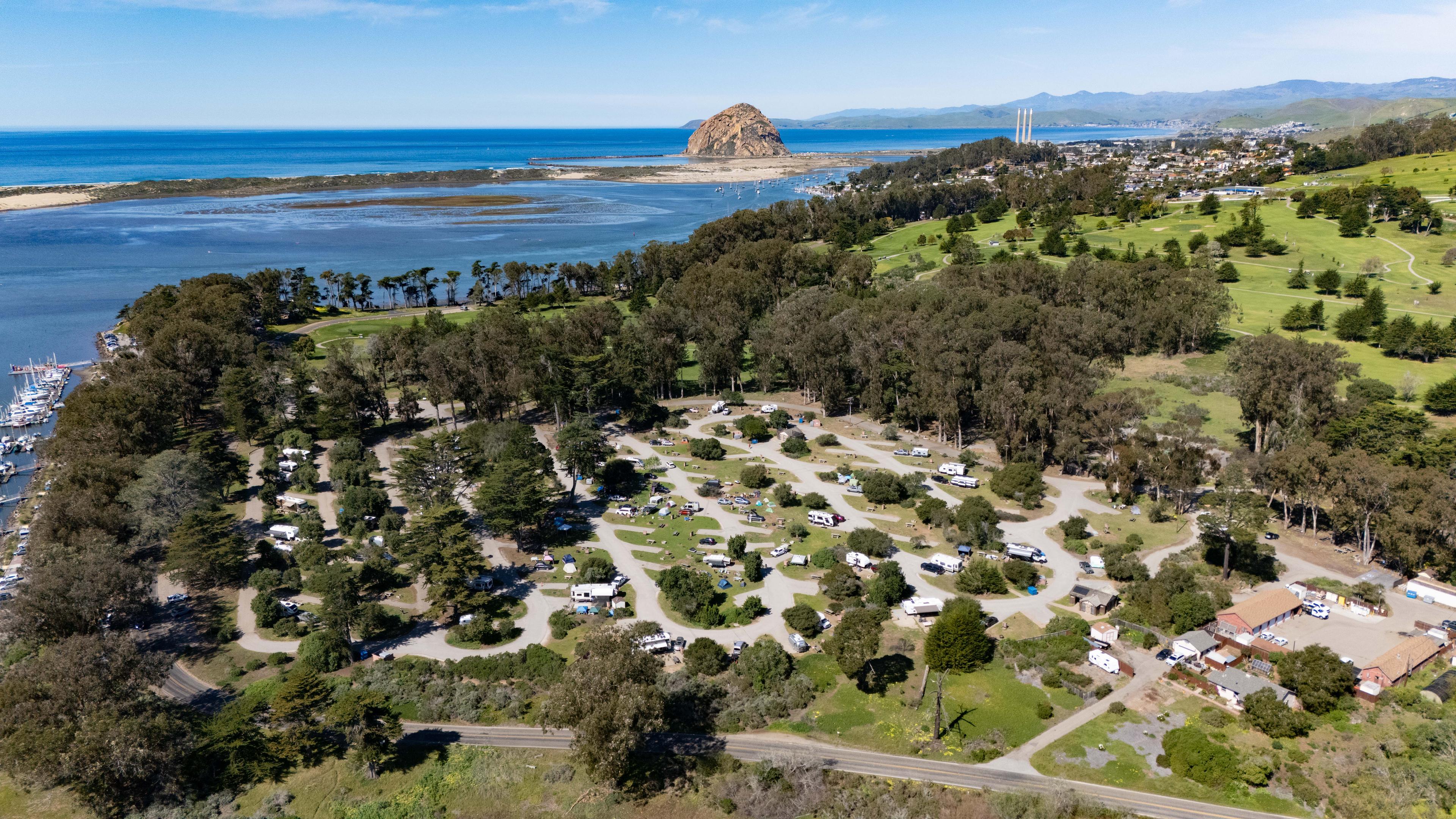 Aerial view of Morro Bay State Park Campground nestled in trees with Morro Rock and the bay in the background Aerial view of Morro Bay State Park Campground nestled in trees with Morro Rock and the bay in the background