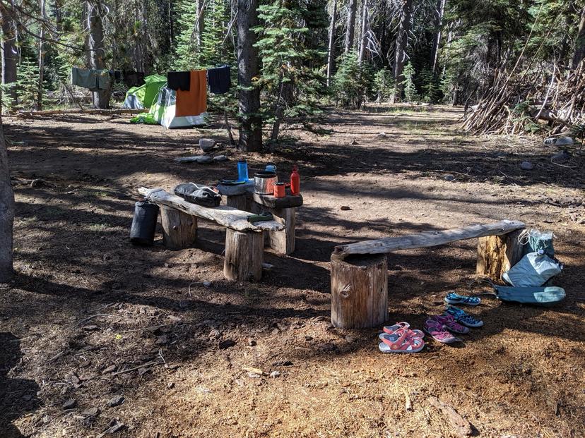Backcountry campsite in Lassen with a tent, clothes drying on a line, and camp shoes lined up on a log bench