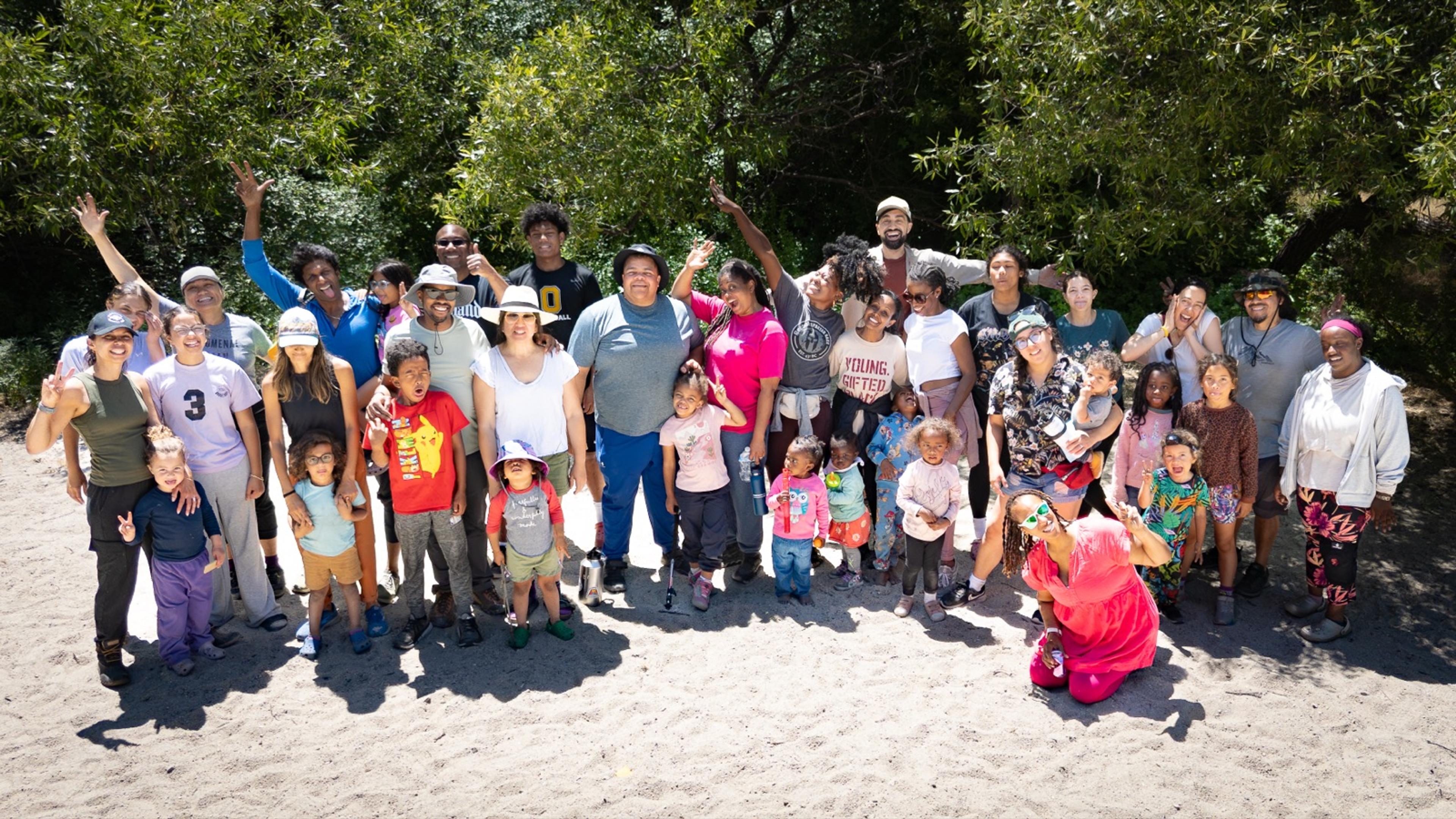 Outdoorithm Collective group photo at Pinnacles National Park, around 40 people gathered on a sandy clearing surrounded by trees