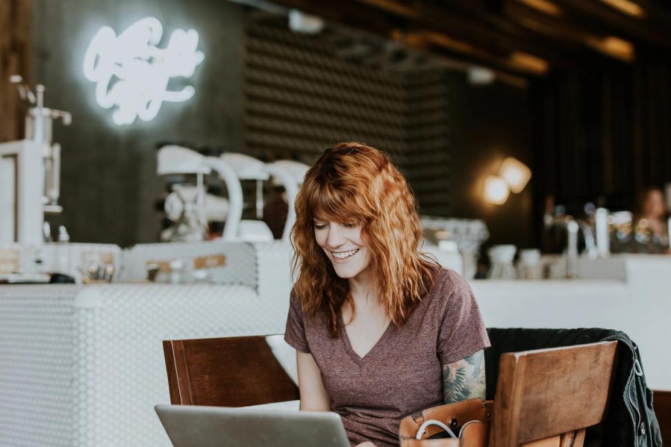 Lady smiles while working at her laptop in an empty restaurant