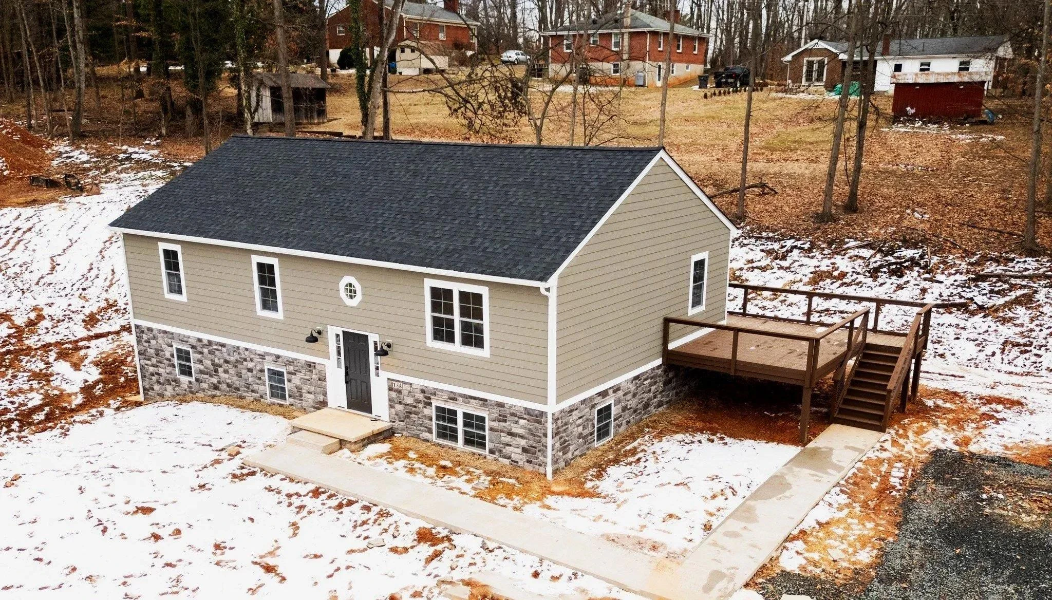 Finished custom home with stone foundation, gray siding, and rear deck