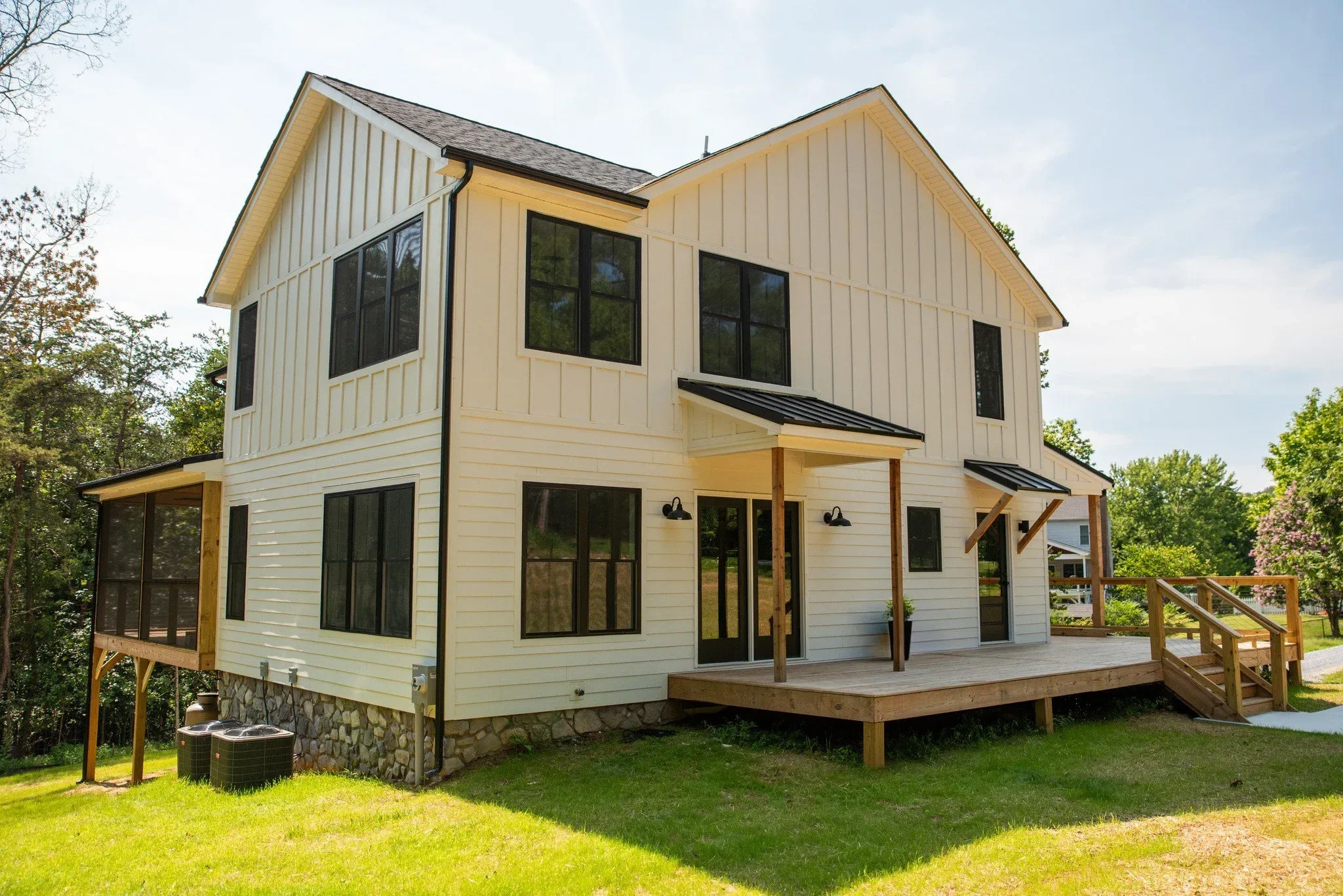 A modern two-story house with white siding and black window frames, with a front porch and steps.