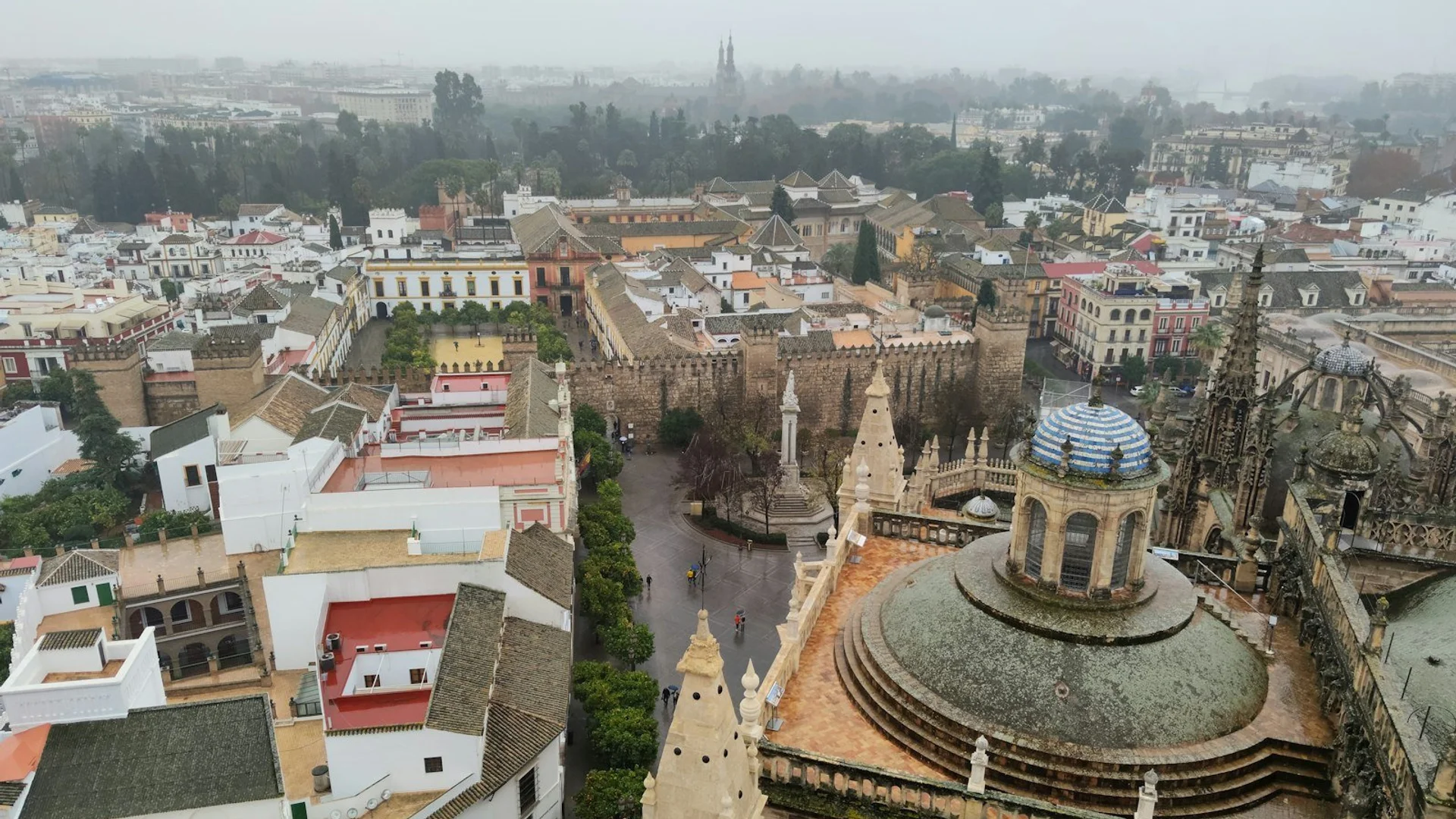 Vista panorámica de la Catedral de Sevilla y la Giralda al atardecer, con el casco histórico iluminado