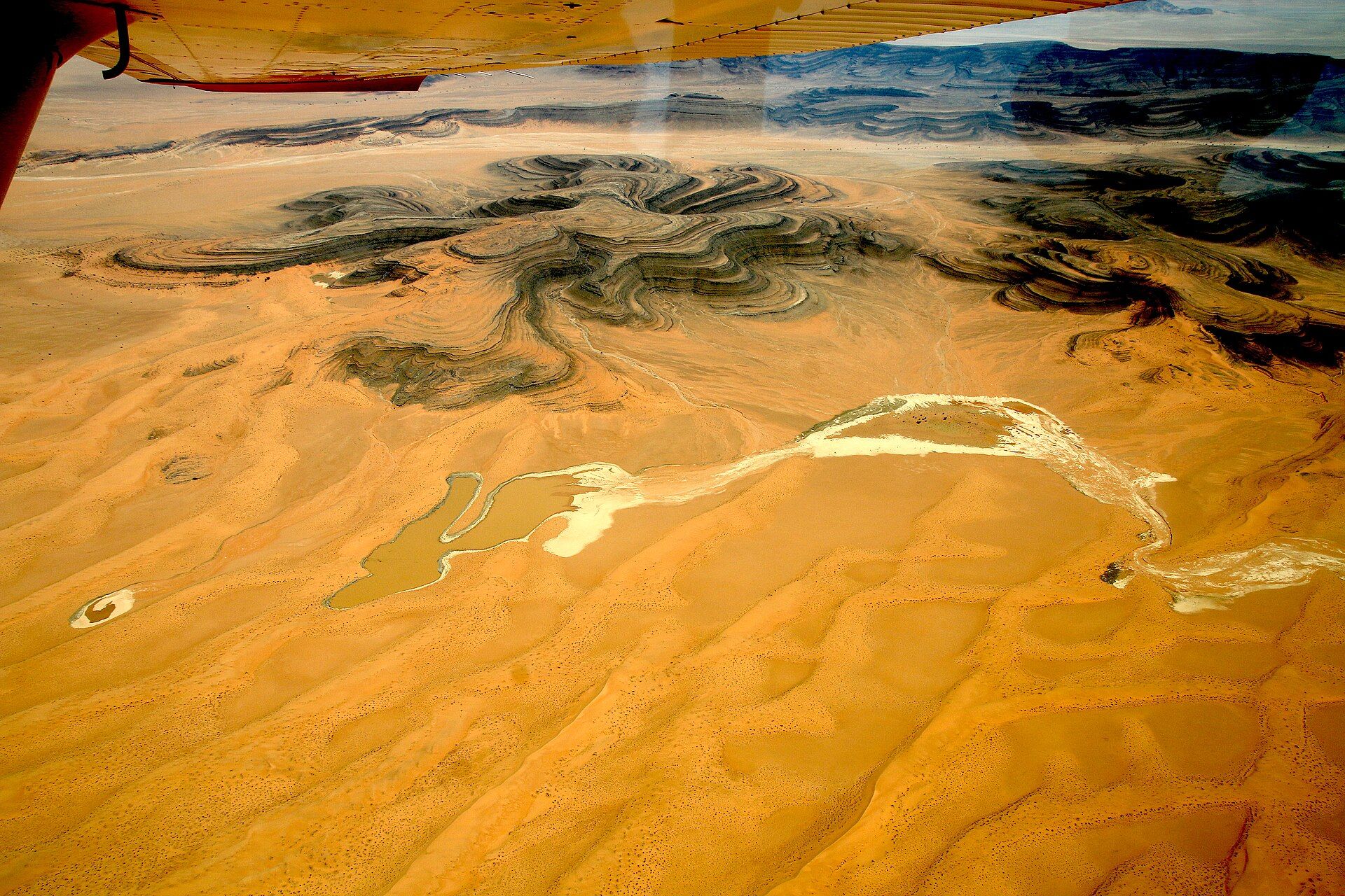Vista aérea del desierto de Namibia con formaciones rocosas oscuras y cauces de ríos secos.