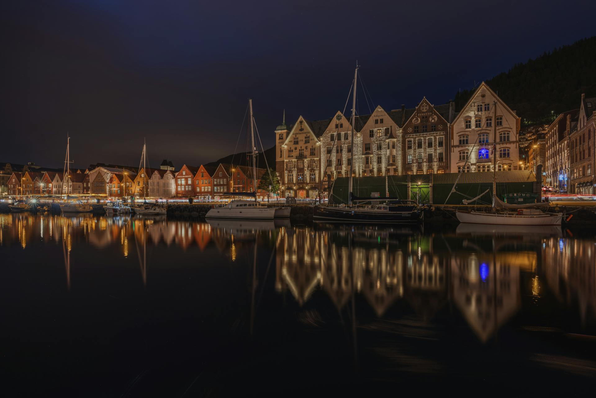 Vista panorámica de Bryggen, el histórico muelle hanseático de Bergen con sus características casas de madera coloridas reflejándose en el puerto de Vågen, rodeado de montañas verdes