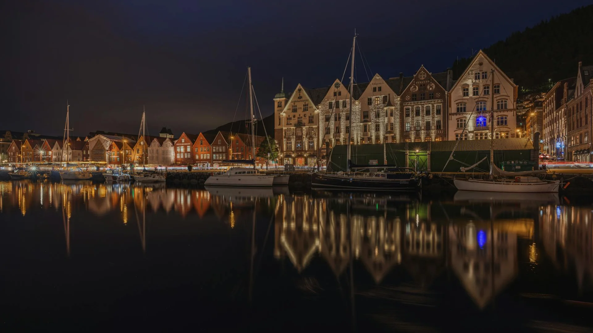 Vista panorámica de Bryggen, el histórico muelle hanseático de Bergen con sus características casas de madera coloridas reflejándose en el puerto de Vågen, rodeado de montañas verdes