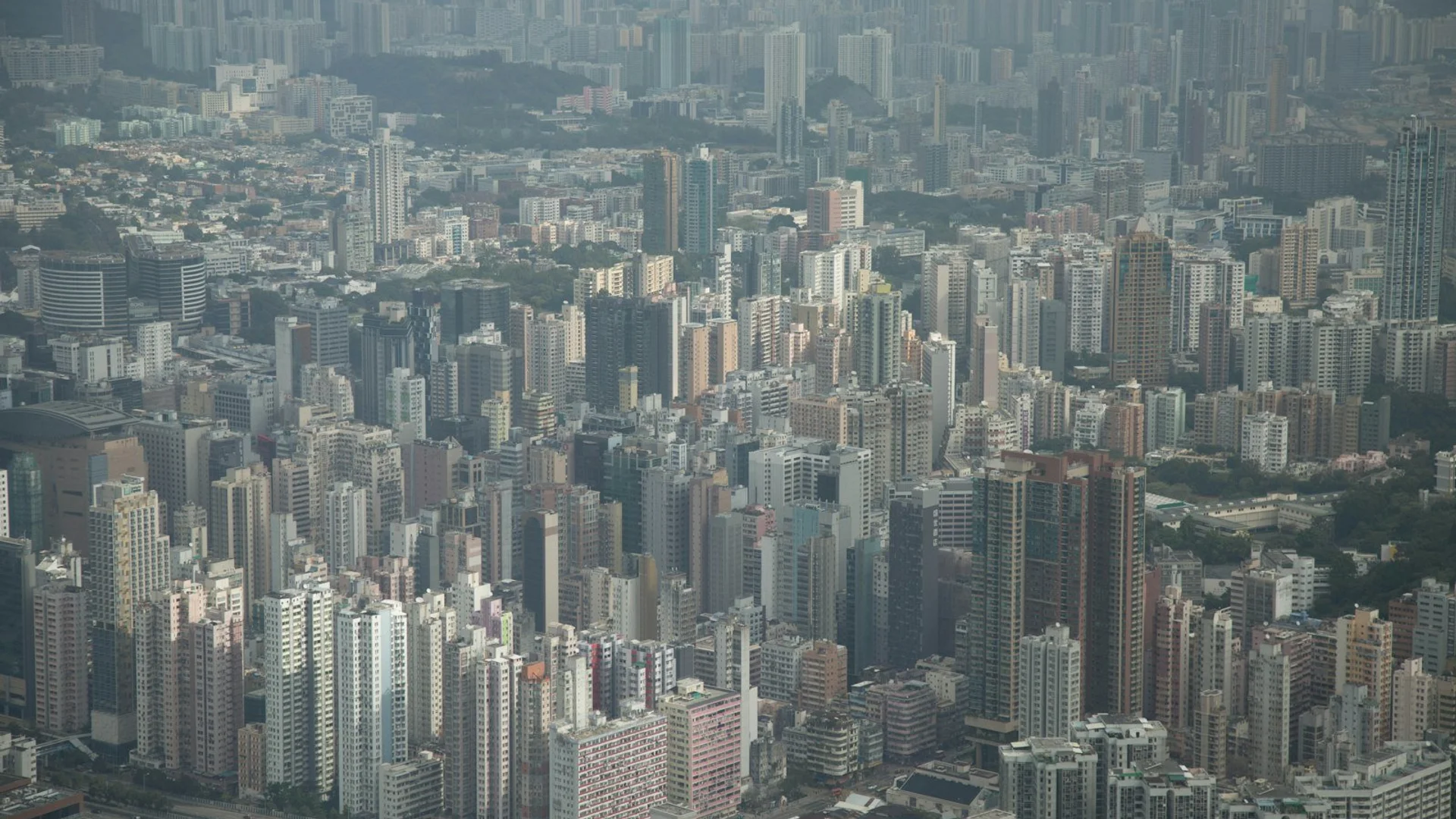 Vista panorámica nocturna del puerto Victoria de Hong Kong con rascacielos iluminados reflejados en el agua