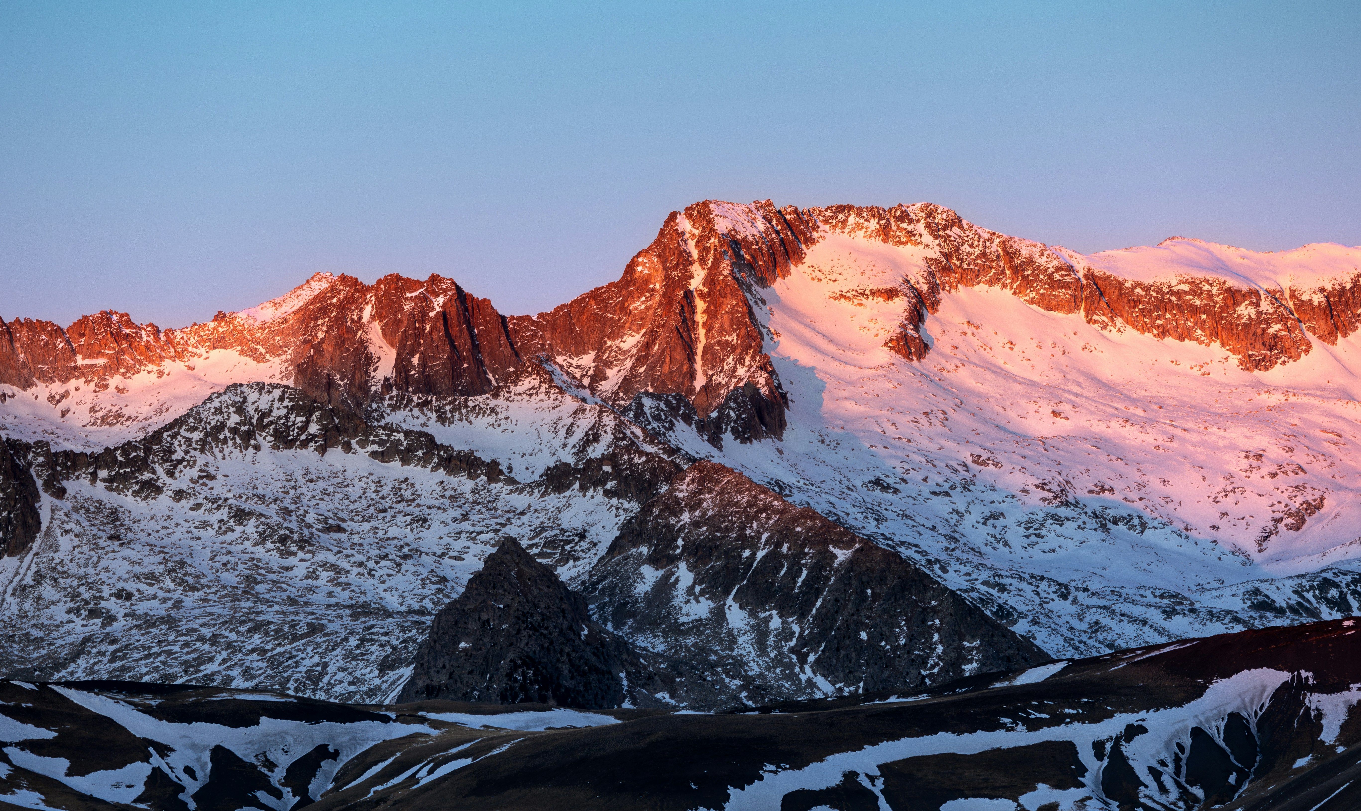 Cumbres montañosas nevadas iluminadas por el sol del amanecer o atardecer.