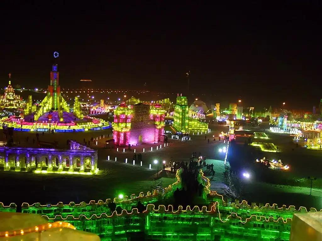 Esculturas de hielo y nieve iluminadas en tonos rosas, verdes y púrpuras forman torres y murallas en la noche del Festival de Harbin