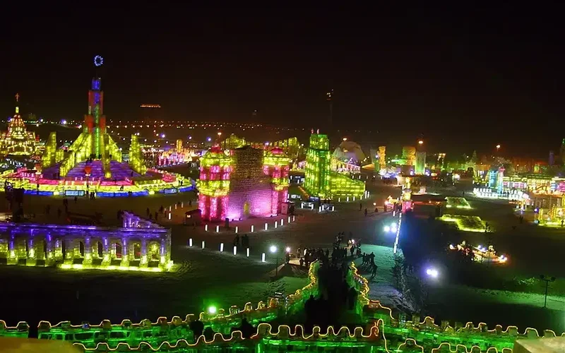 Esculturas de hielo y nieve iluminadas en tonos rosas, verdes y púrpuras forman torres y murallas en la noche del Festival de Harbin