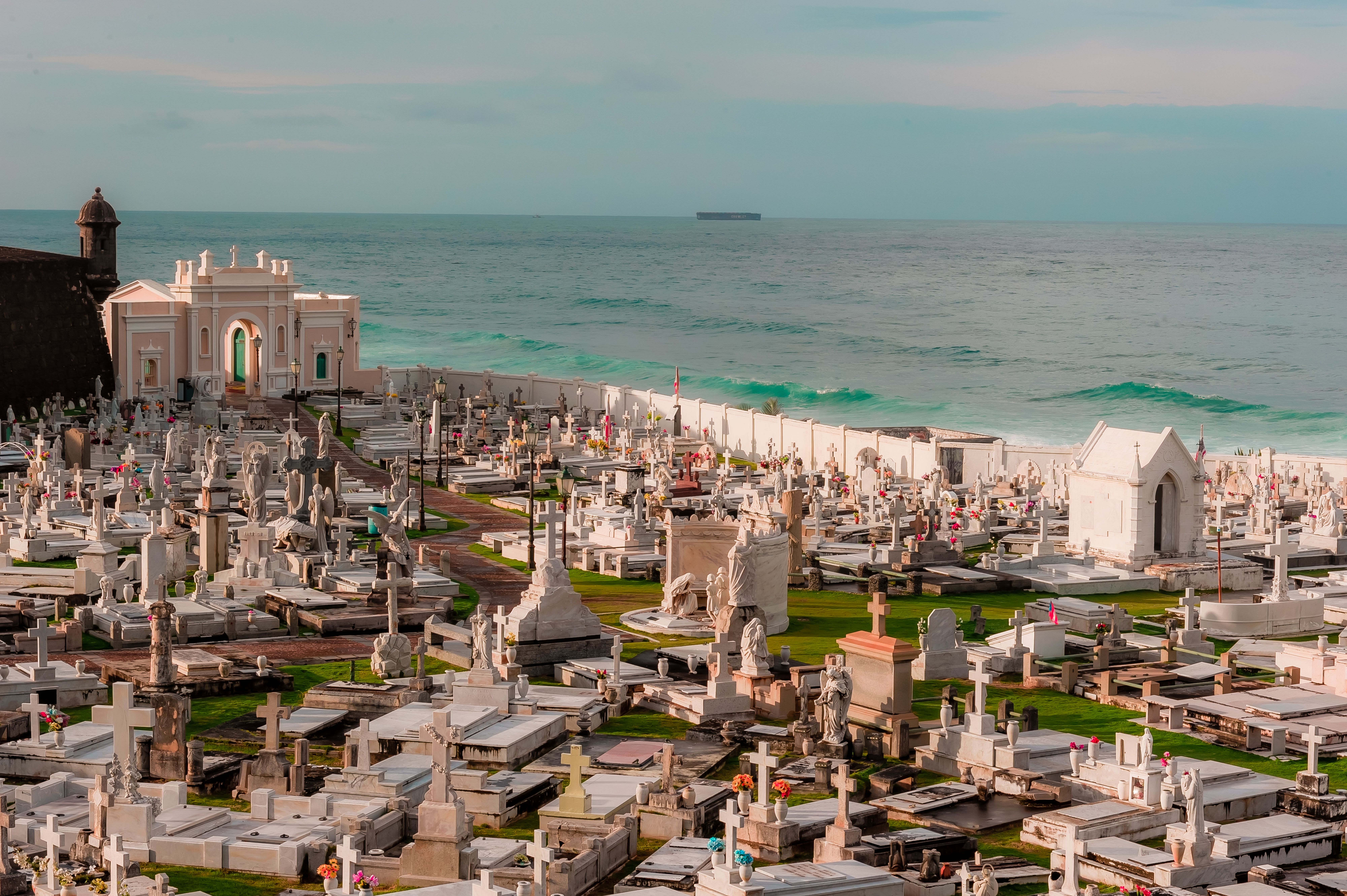 Vista aérea de un cementerio costero con numerosas tumbas blancas y el océano al fondo.