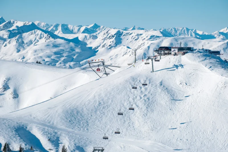 Pistas de esquí nevadas con remontes y edificios de estación en un paisaje montañoso.