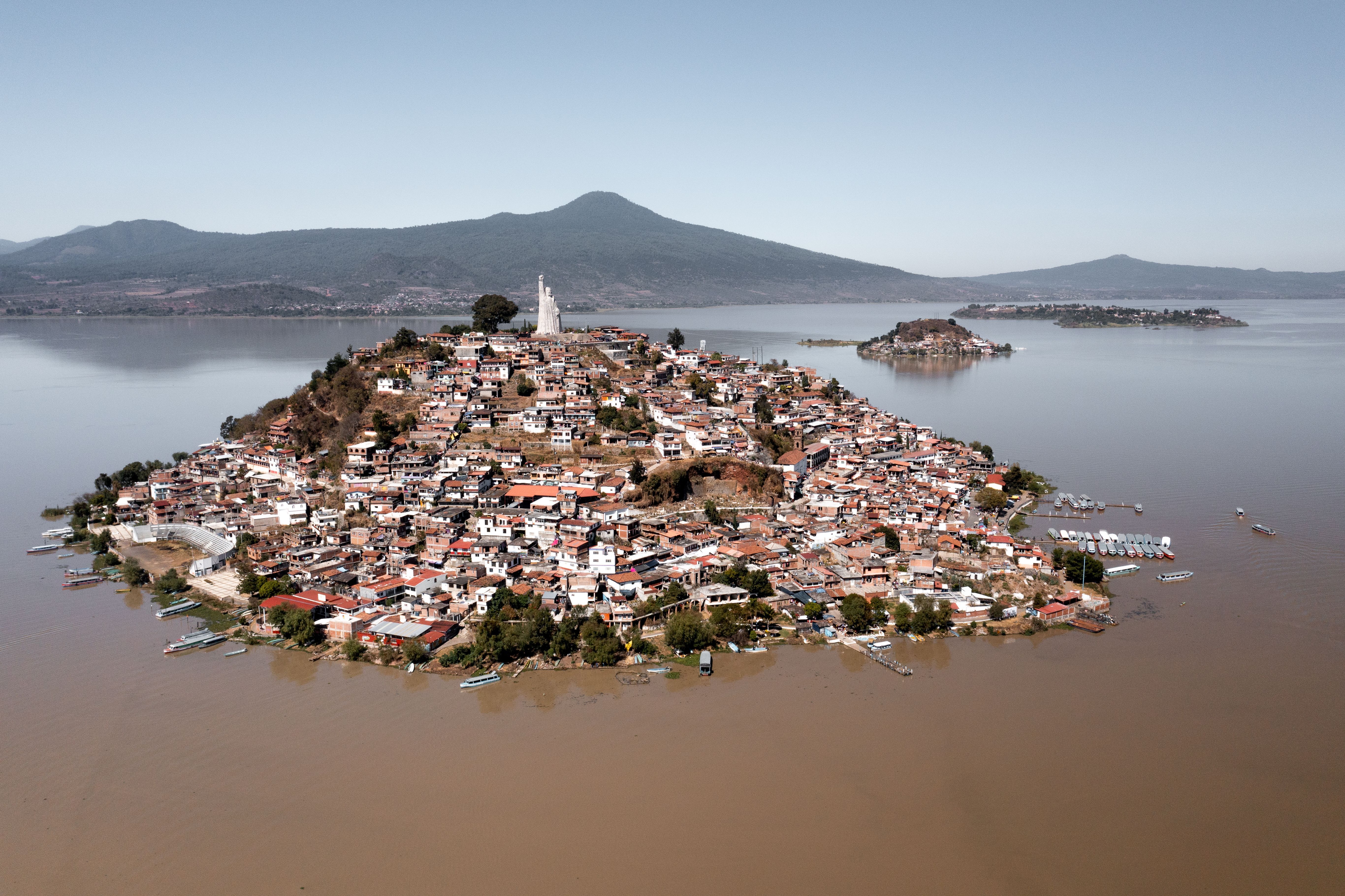 Vista aérea de la isla de Janitzio en el lago de Pátzcuaro, con casas y una estatua.