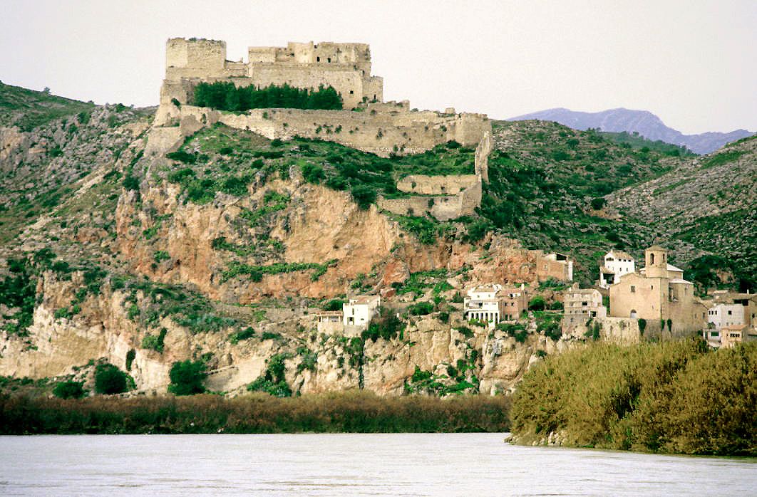 Vista panorámica de un castillo templario en lo alto de un acantilado rocoso junto a un río.