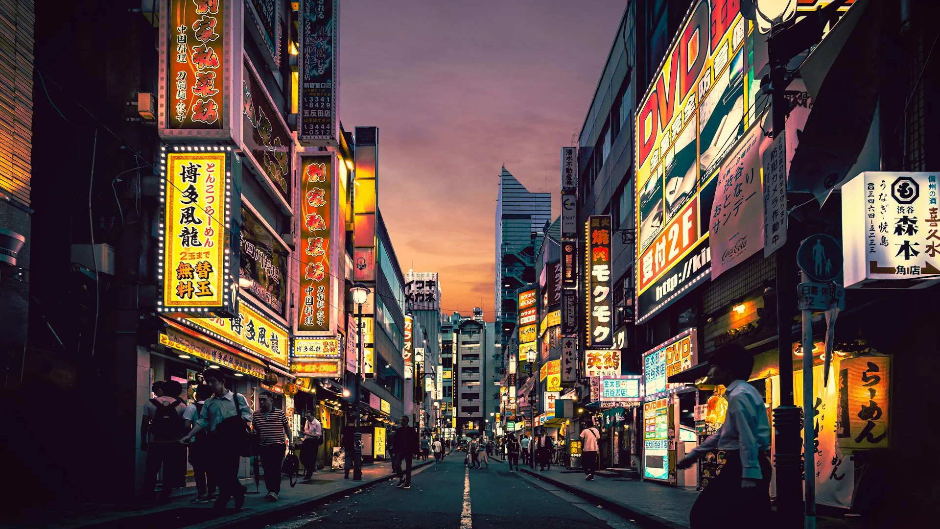 Vista de una calle vibrante en Tokio al atardecer, con neones y letreros en japonés iluminando fachadas, peatones caminando