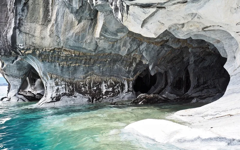 Formaciones de mármol gris y blanco con cuevas sobre agua turquesa y azul en la Patagonia.