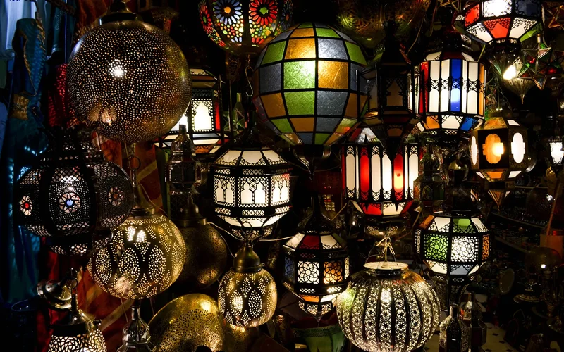 Lámparas tradicionales multicolores colgando en un bazar, con patrones geométricos perforados y luces suaves