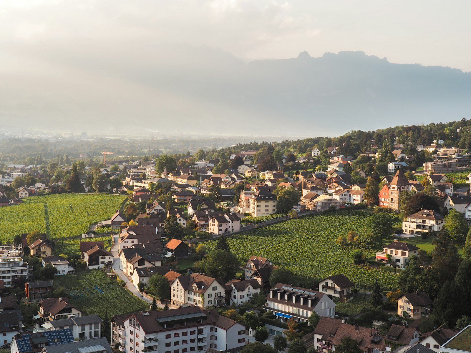 Gentle and soft sunlight shines on the fields and the city of Vaduz.