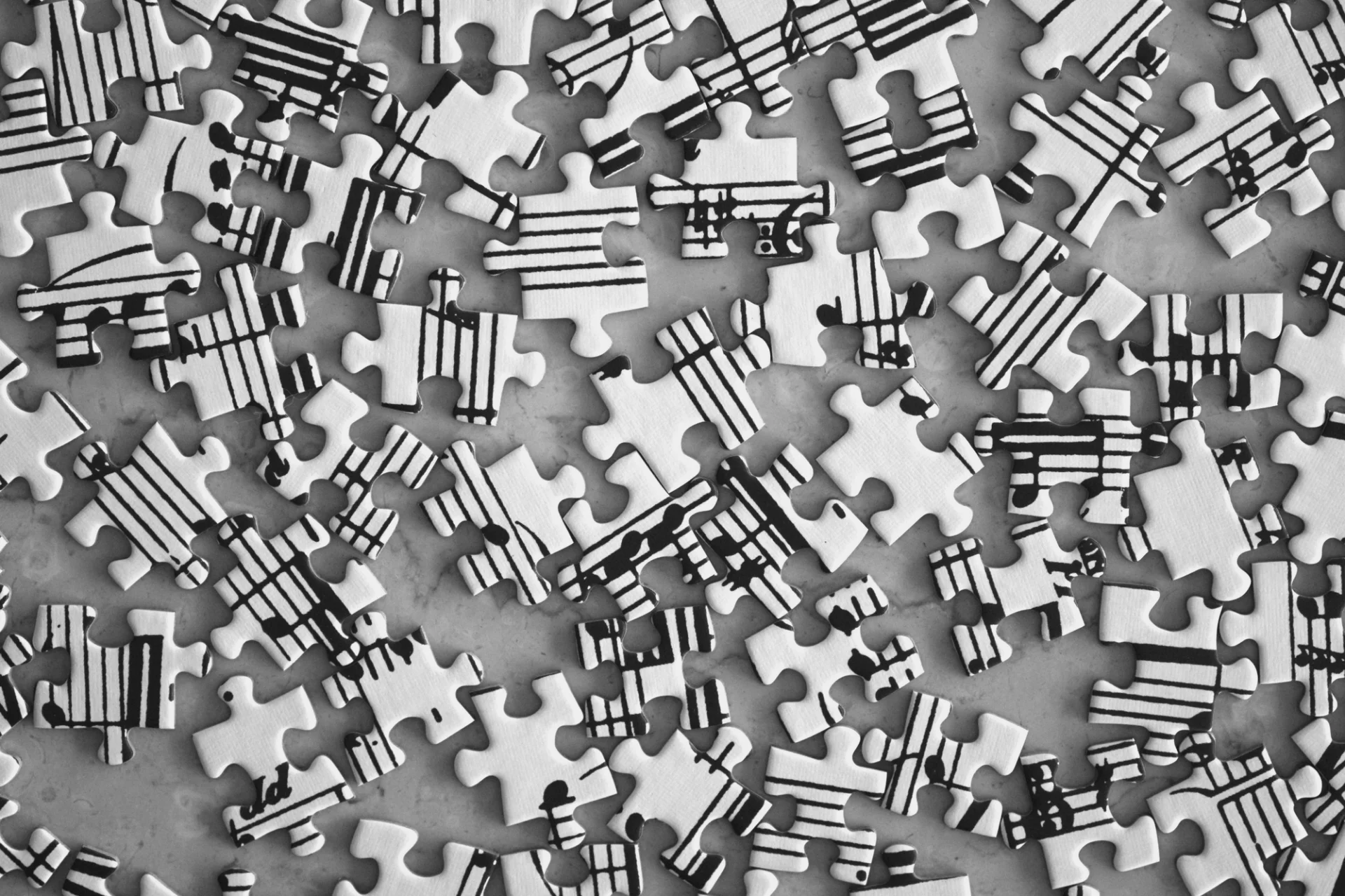 Piezas de rompecabezas blancas y negras dispersas, cada una con fragmentos de partituras musicales.