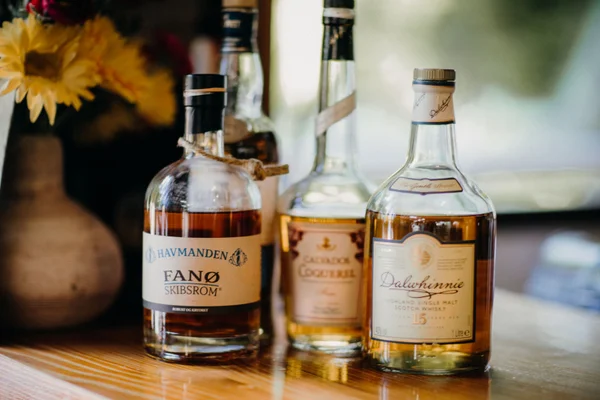 Varias botellas de licor, incluyendo whisky Dalwhinnie, sobre una superficie de madera.
