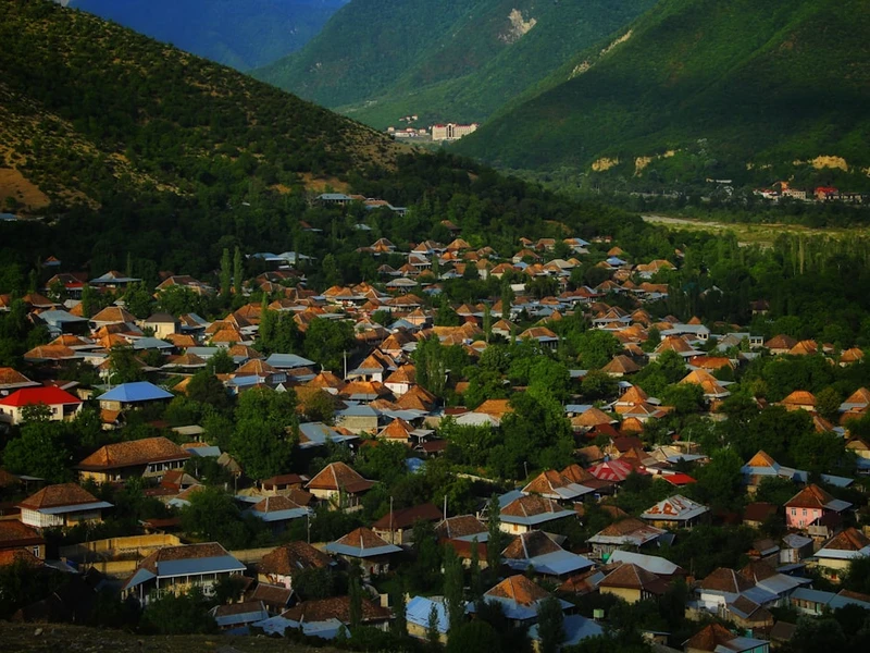 Vista panorámica de Sheki, con casas de techos rojos y coloridos en un valle verde rodeado de montañas
