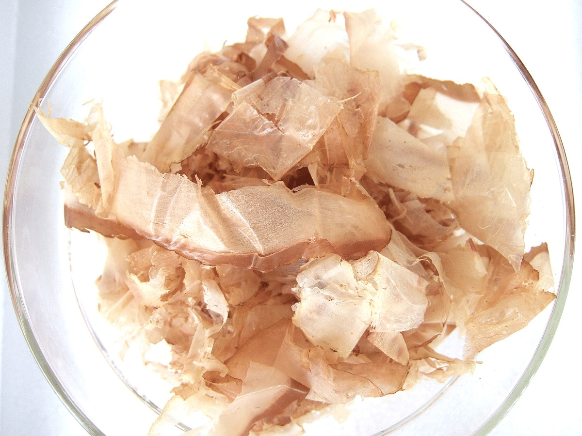 Cuenco transparente lleno de hojuelas de katsuobushi, copos de pescado seco japonés de tono beige claro