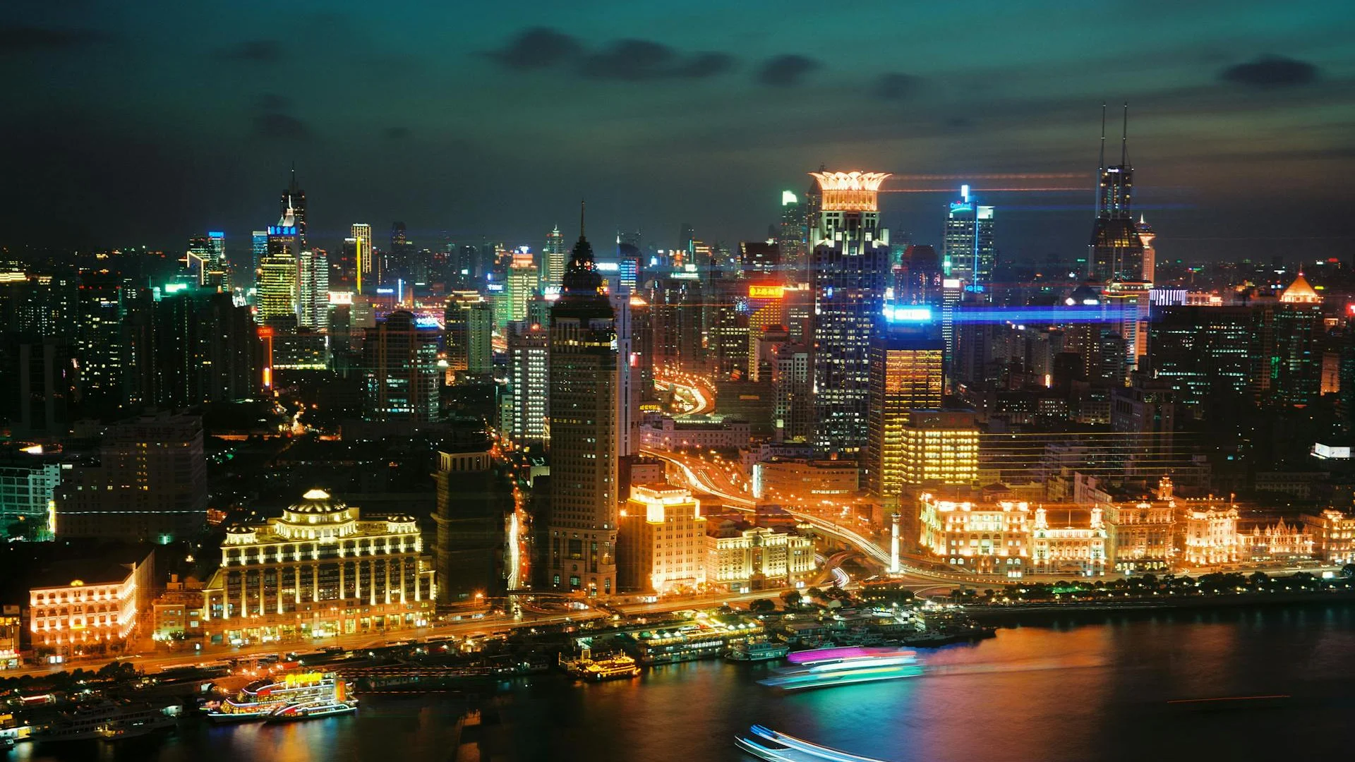 Vista nocturna de la skyline de Shanghái con rascacielos iluminados en Pudong y el Bund junto al río Huangpu
