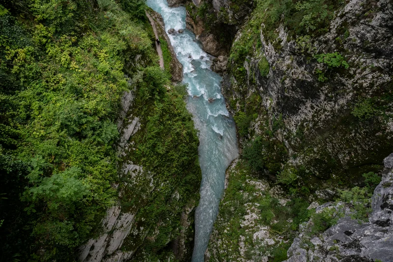 Vista aérea de un río azul turquesa serpenteando entre paredes rocosas cubiertas de vegetación verde.