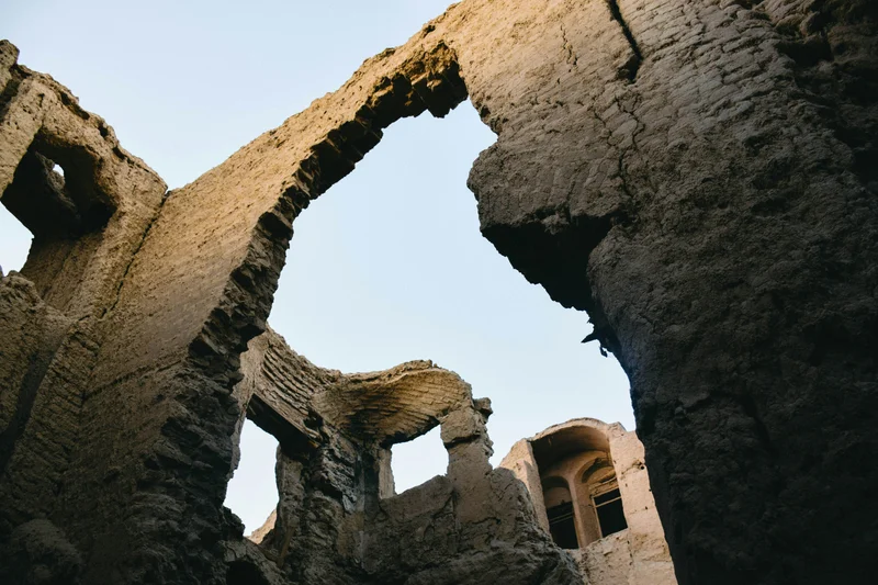 Ruinas de una edificación de adobe con arcos y huecos de ventanas contra un cielo claro.