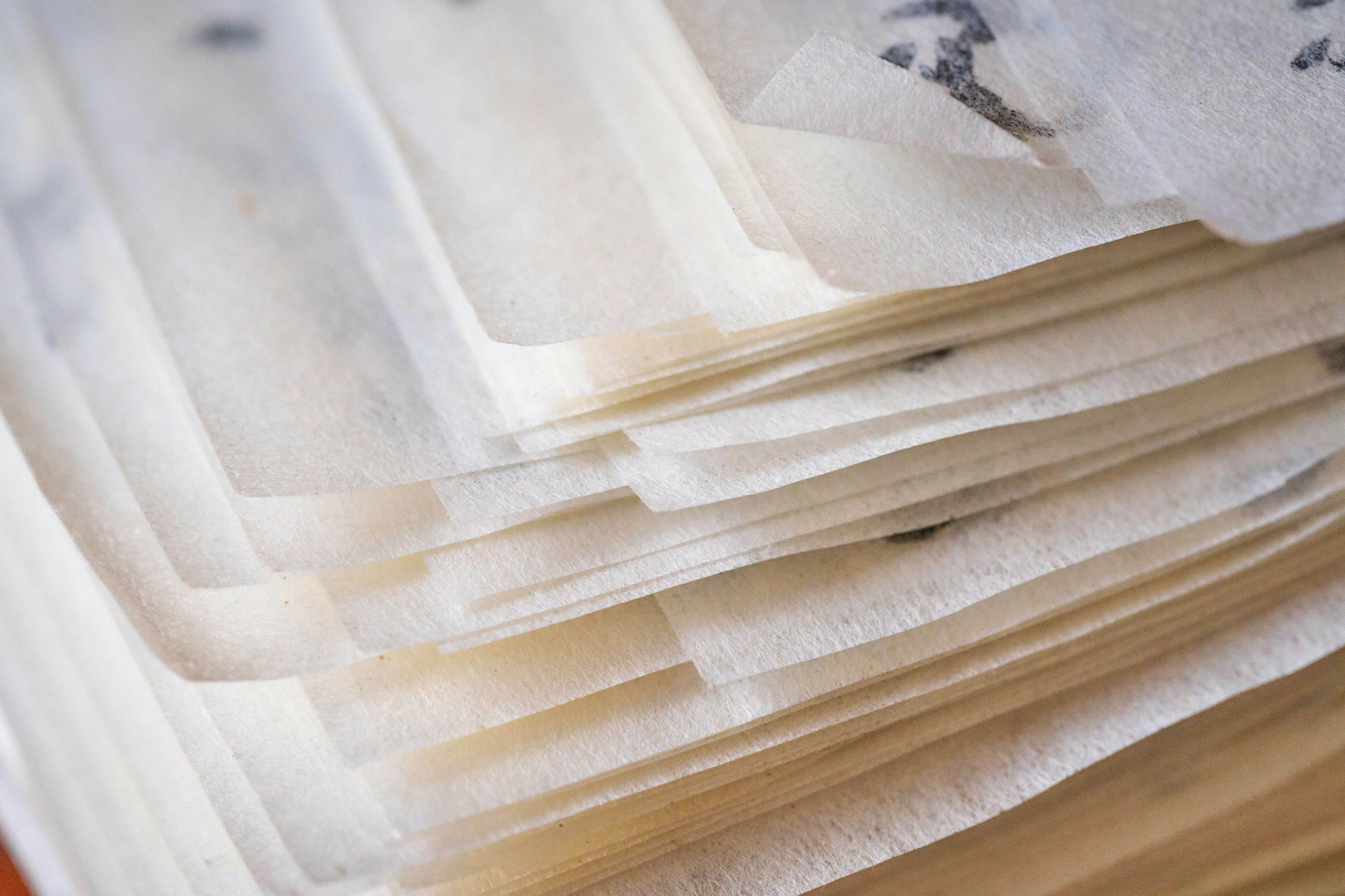 Primer plano de una pila de hojas de papel translúcido y fino con bordes ligeramente irregulares.